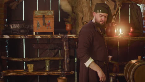 a man dressed in medieval clothing stands in a tavern.