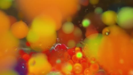 Multi-colored-water-gel-balls-moving-and-swirling-past-the-screen,-beautiful-lime-green-with-orange-and-deep-blue-abstract-background