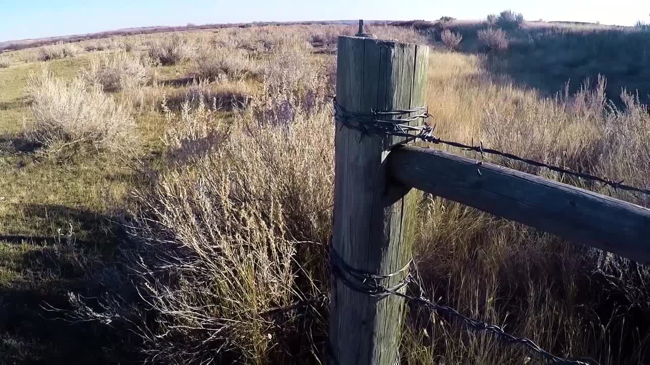 valla de madera de alambre de púas con un campo de hierba en el campo
