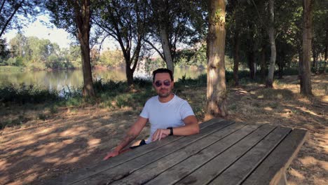 man sitting at a wooden table in the forest