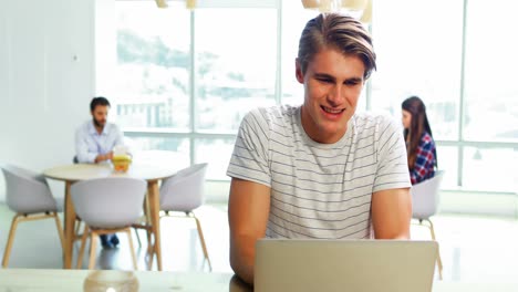 Male-executive-sitting-at-desk-and-using-laptop