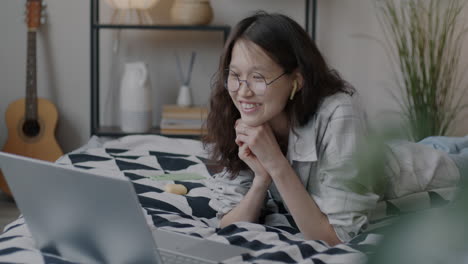 young woman having a video call on laptop in bedroom