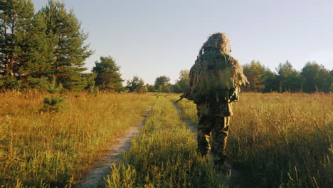 Hombres-Armados-En-Camuflaje-Caminando-A-Lo-Largo-De-Un-Camino-Rural-Vista-Posterior