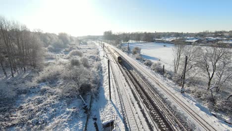 Fast-train-followed-by-an-fpv-drone,-on-a-snowy-sunset