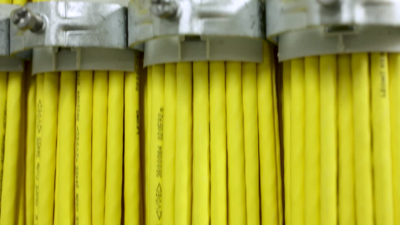 Extreme close-up tedious arranged yellow cables fixed with metal clamp