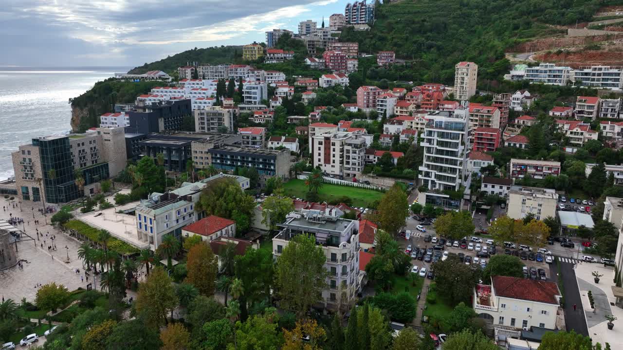 Coastal residential buildings and hillside homes near Budva Old Town in Montenegro. Aerial view, pan left