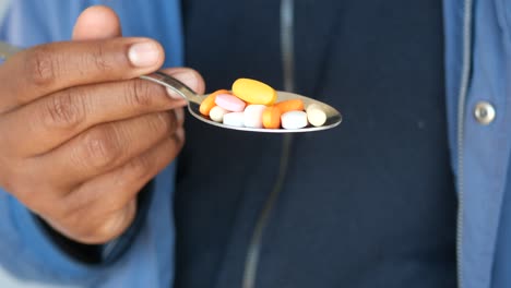person holding a spoon with pills
