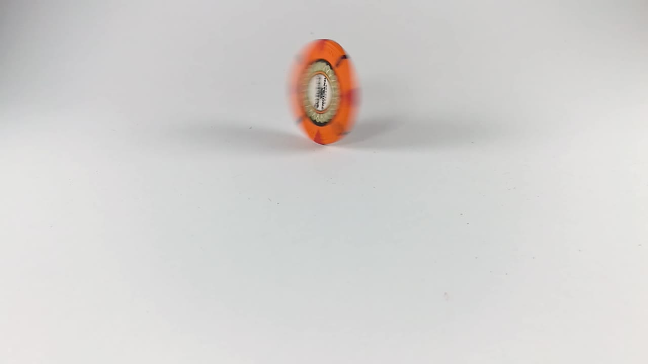 una ficha de póquer naranja girando sobre una mesa blanca, todavía, aislada, slomo