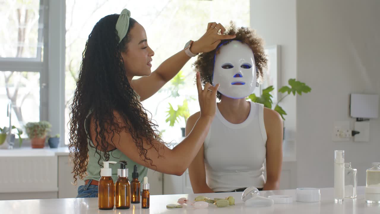 Afroamerikanske veninder samles omkring serummer og tilpasser LED-masker, mens de demonstrerer lys ved en disk.