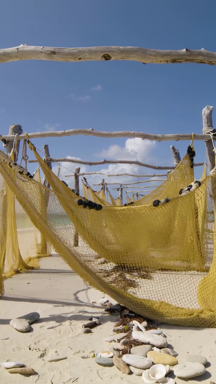 Vertical video: Light breeze swaying yellow fishing nets shifting on shore, drying with buoys