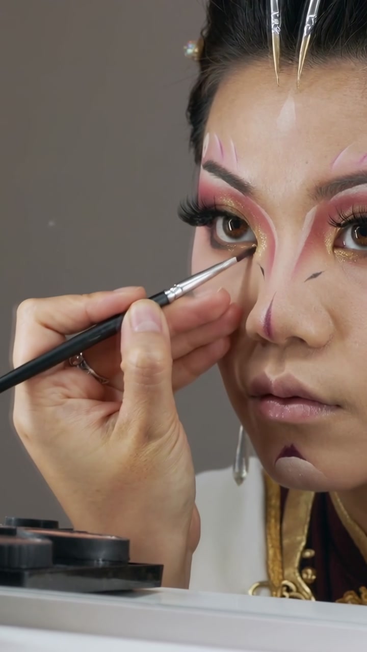 Vertical video: Entering frame artist lining model lash in studio with brush, gold collar for show