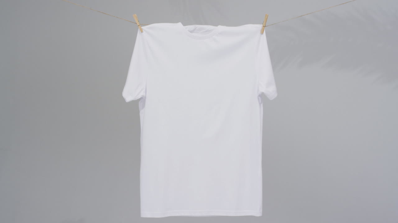 회색 배경에 옷 스 ⁇ 과 복사 공간을 가진  ⁇  티셔츠의 비디오