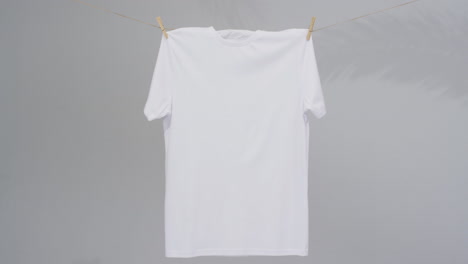 video de camiseta blanca con clavijas de ropa y espacio de copia en fondo gris