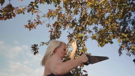 hembra adulta usando una sierra para cortar las ramas de los árboles en cámara lenta