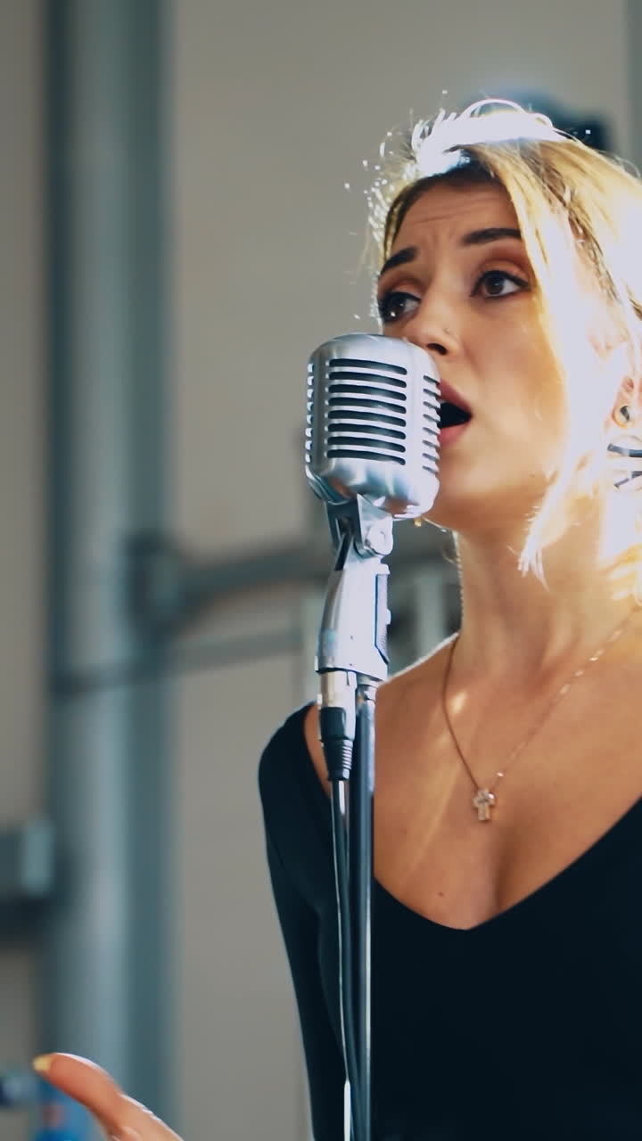 Portrait of a beautiful young singer. Blonde woman standing on the stage and singing into the microphone. Slow motion. Vertical video