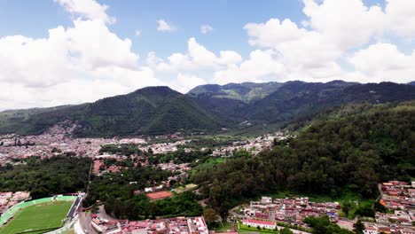 Captura-Aérea-De-Una-Hermosa-Ciudad-Situada-Entre-Las-Exuberantes-Colinas-Verdes