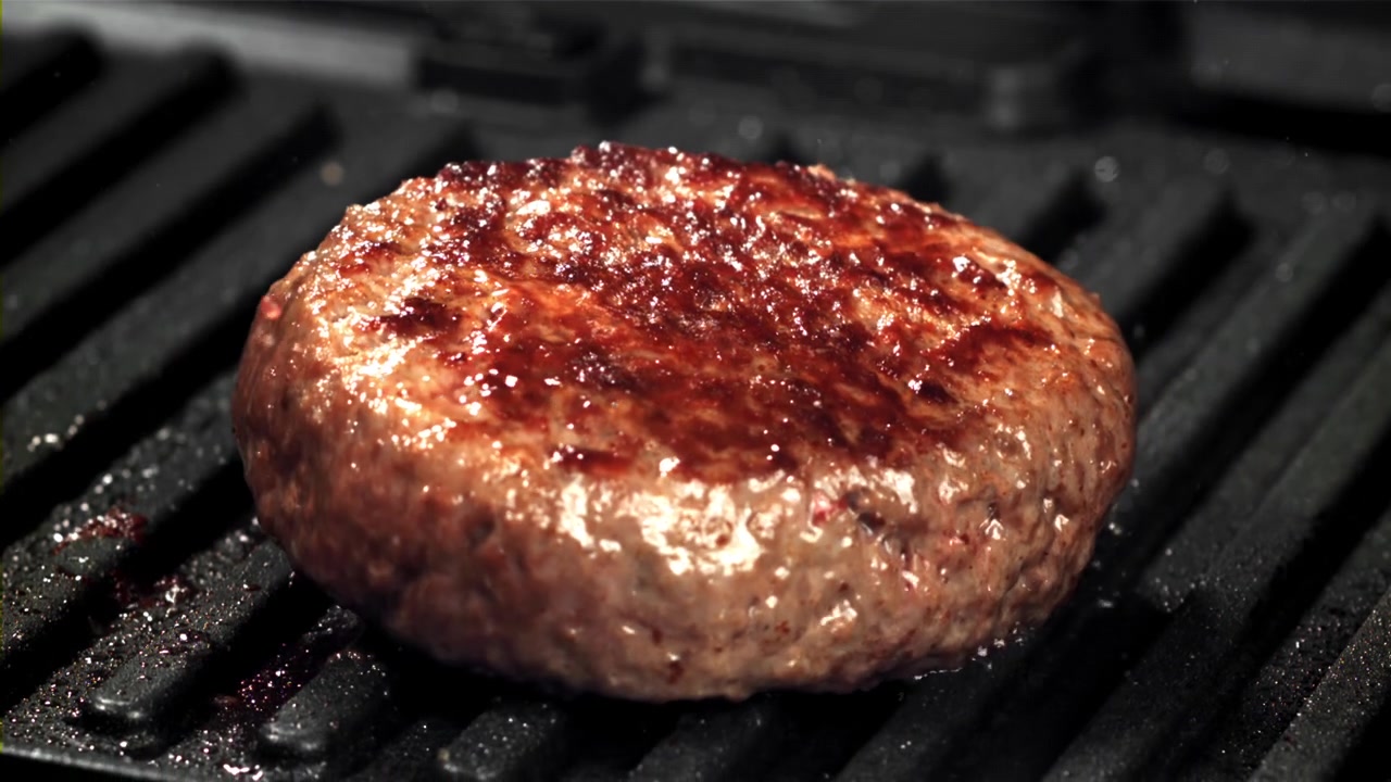 Close-up of a Raw Hamburger Patty Sizzling on a Hot Grill
