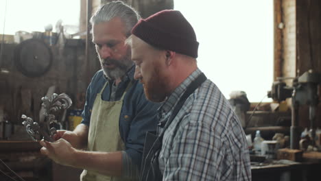 two blacksmiths discussing iron details at work