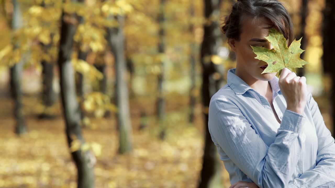 Sunny autumn day in park. Young woman spending time in autumn park