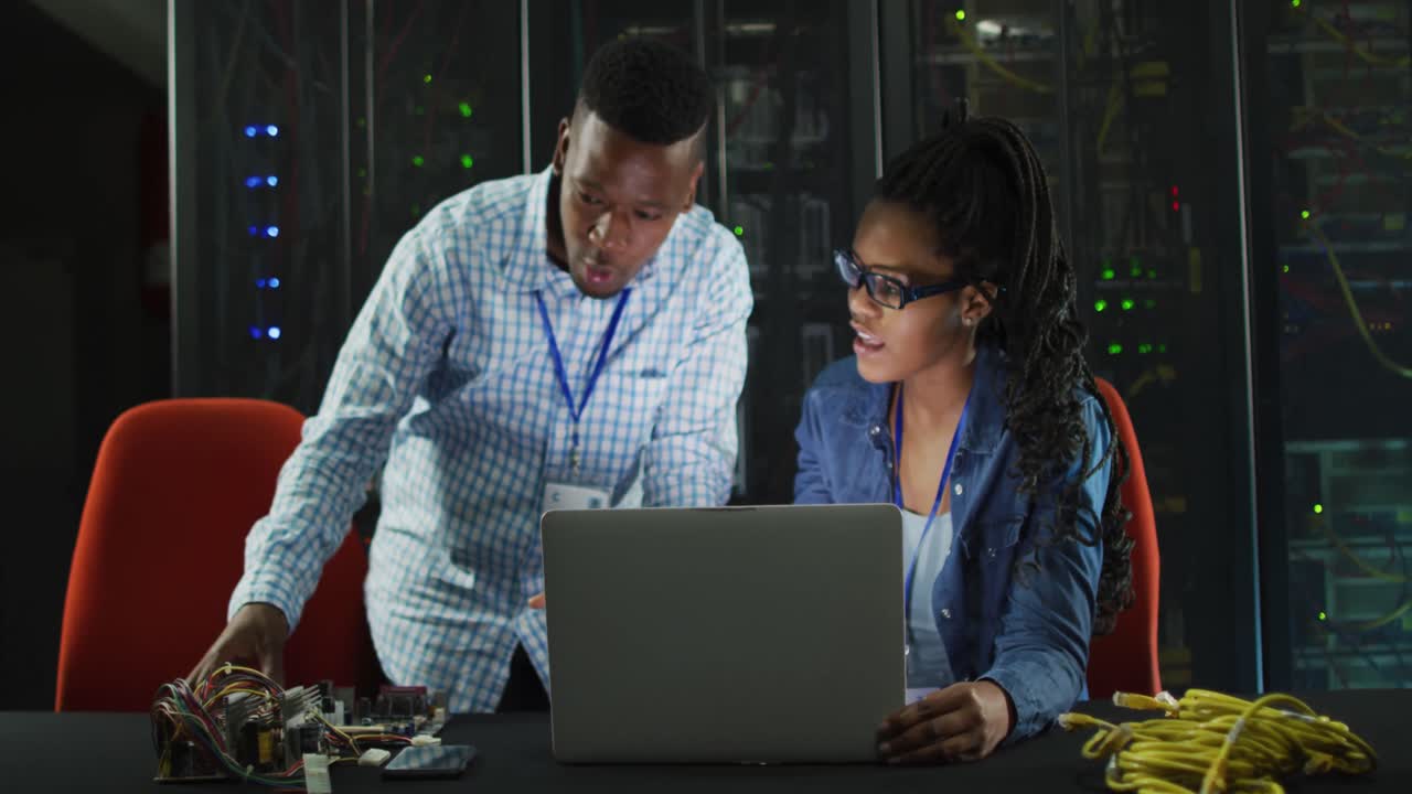 African american computer technicians using laptop working in business server room