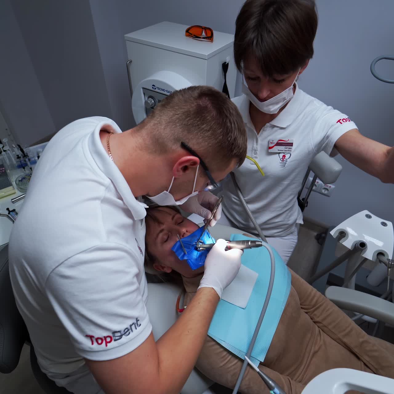 Female patient at dental specialist's check up. Woman lies with eyes closed at stomatology cabinet while dentist treats her teeth