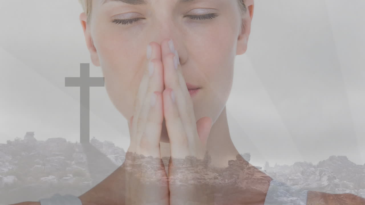 Praying, woman with hands together, cross and landscape in background