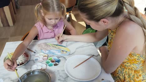madre e hija pintando una placa de cerámica