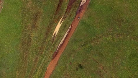 Jinete-De-Motos-De-Cross-Pasando-Por-Una-Pista-Fangosa,-Vista-Superior-De-Un-Disparo-De-Un-Dron