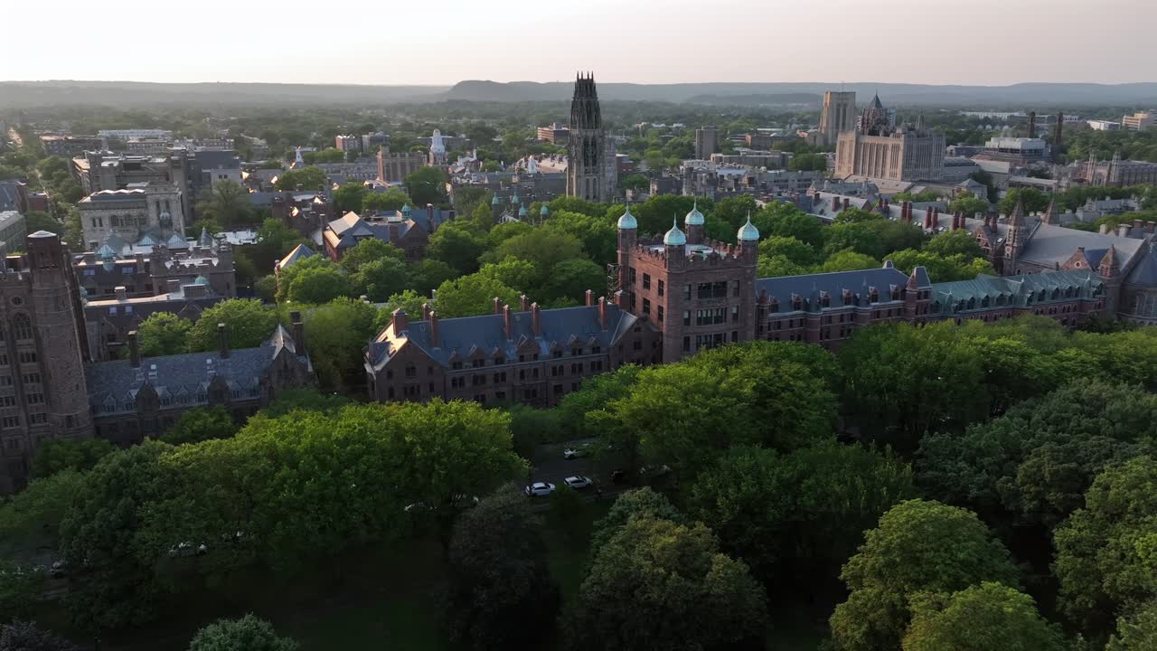 Golden sunrise in New Haven City. Historic Yale university campus with gothic buildings and harkness tower. Aerial approaching wide shot. Connecticut, USA in summer