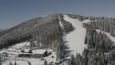 kope ski resort ribnica one track with descending skiers and snowboarders, aerial approach shot