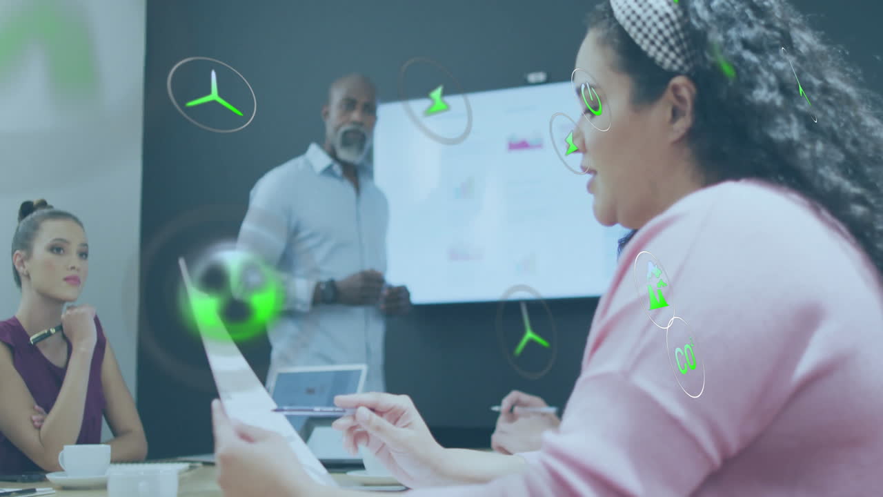 Animation of ecology icons over diverse colleagues having meeting in office