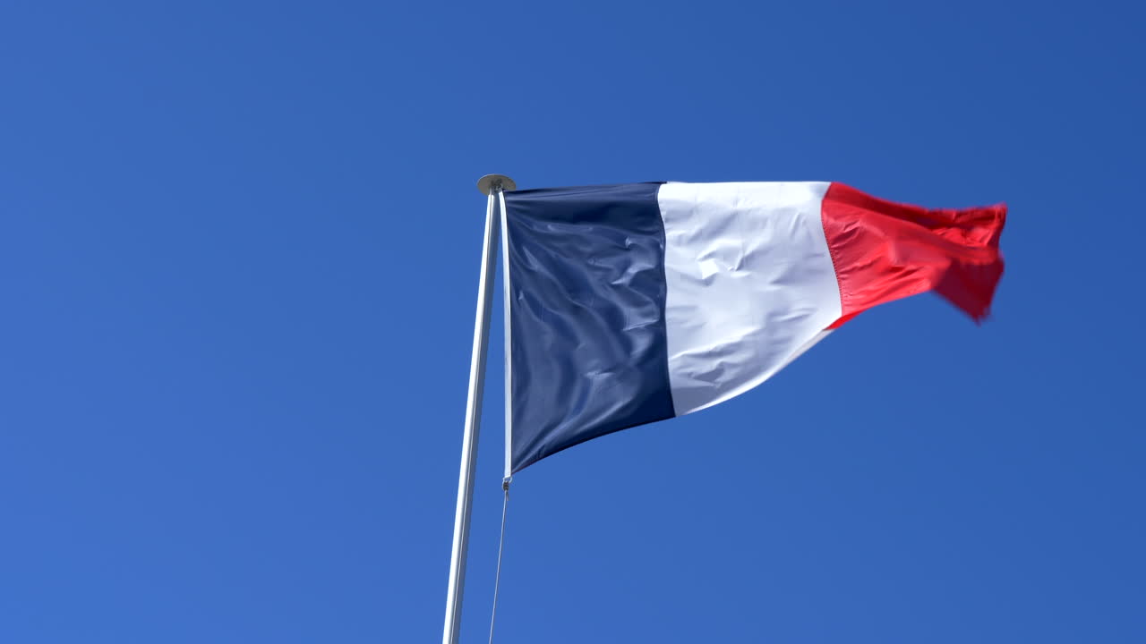 Primo piano della bandiera francese che sventola al vento, sfondo cielo blu, slow motion 4K