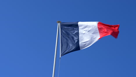 cerrar la bandera de francia francesa ondeando en el viento, fondo de cielo azul, cámara lenta 4k