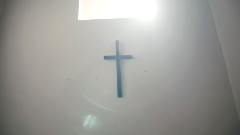 sunlit psychiatric ward with wall cross above bed