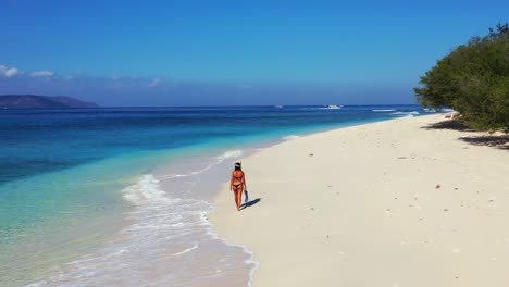 Chica-En-Bikini-Con-Equipo-De-Esnórquel,-Caminando-Sobre-La-Arena-Blanca-De-Una-Playa-Exótica-Junto-A-Las-Olas-Del-Mar-Buscando-El-Lugar-Ideal-Para-Sumergirse-En-La-Laguna-Azul-Turquesa