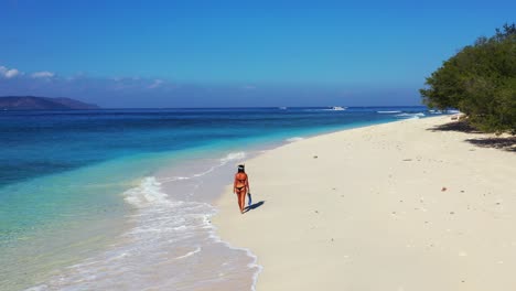 girl in bikini wearing snorkel set, walking on white sand of exotic beach alongside sea waves seeking for ideal place to dive into blue turquoise lagoon