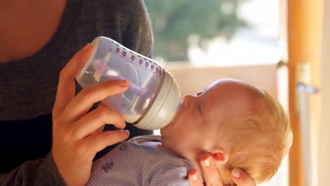 madre alimentando leche a su bebé en la sala de estar 4k