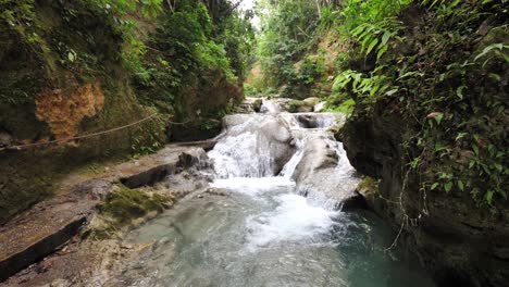 a spectacular view looking up the river of cascading waterfalls and tropical natural pools at the beautiful cool blue hole tourist attraction in ocho rios jamaica with lush vegetation lining the river