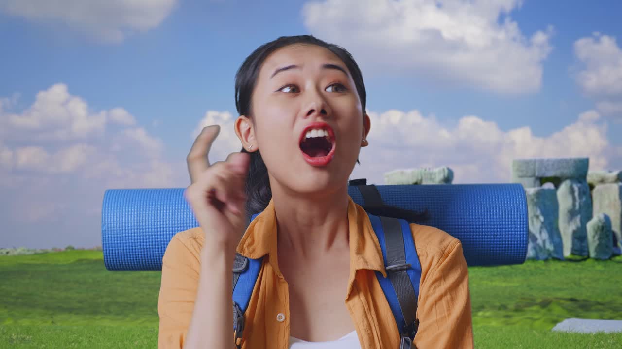 Close Up Of Asian Female Hiker With Mountaineering Backpack Thinking About Something And Looking Around Then Raising Her Index Finger While Traveling In Stonehenge
