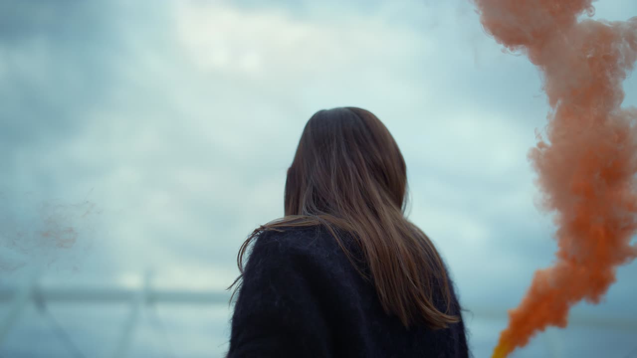 소녀는 연기 폭탄으로 카메라에 손을 흔들고 있다. 젊은 여성이 카메라에 포즈를 취하고 있다