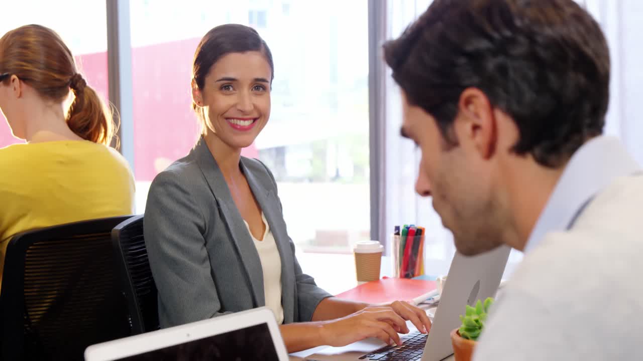 dos colegas trabajando en una computadora portátil en el escritorio