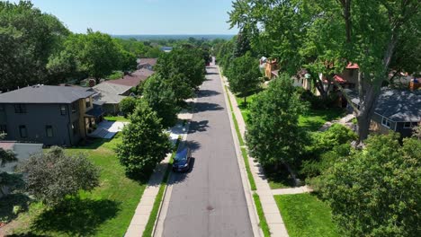 Green-tree-lined-residential-street-with-houses-in-a-suburban-neighborhood