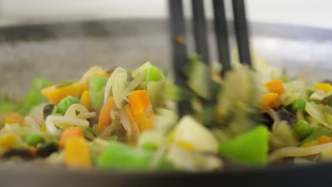 steaming hot vegetables mixed up in a frying pan with a spatula