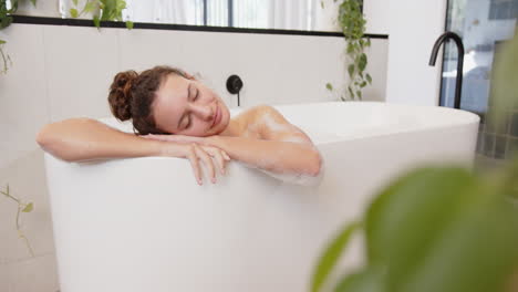 relaxing in bathtub, woman enjoying home day at home with plants around