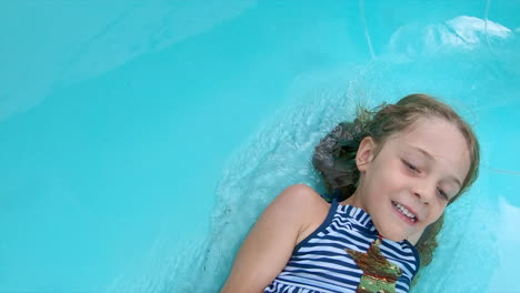 close up of smiling young girl going down a water slide