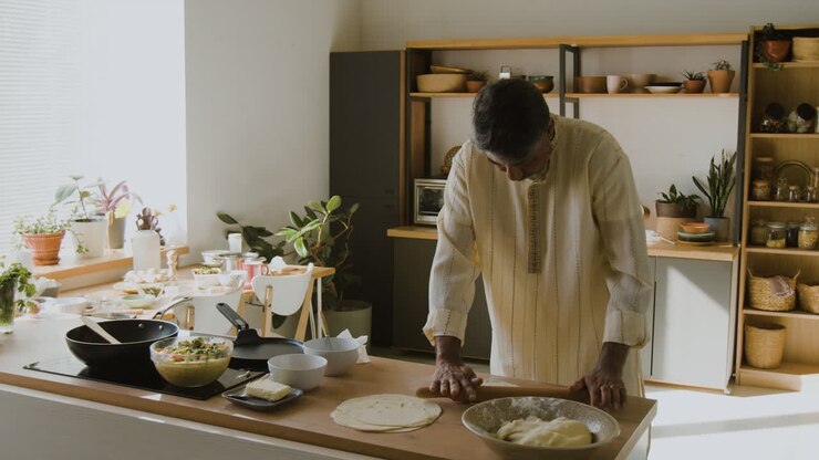 Uomo indiano che cucina pane piatto in una cucina moderna