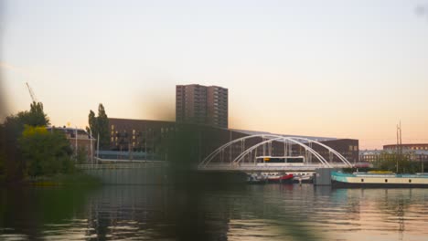 Video-of-a-bridge-over-water-in-Amsterdam-with-blurred-foliage-in-the-foreground-during-sunset