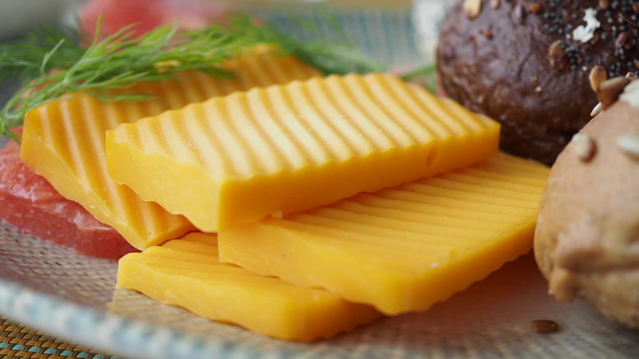 Gros plan sur des tranches de fromage, des petits pains et de l'aneth frais sur une assiette