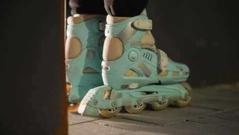 side view of a pair of blue rollerblades gently rolling in place against a dark nighttime background. the scene highlights the smooth, controlled movement and the details of the rollerblades' design