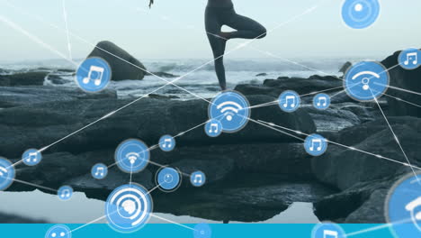 network of connection icons against woman practicing yoga near sea shore